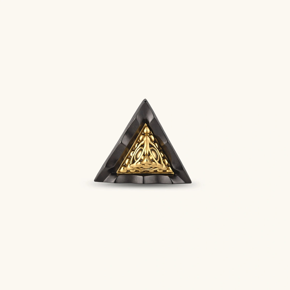 Single black triangle stud earring with a raised gold-tone center, beaded trim and eye motif on a cream background.