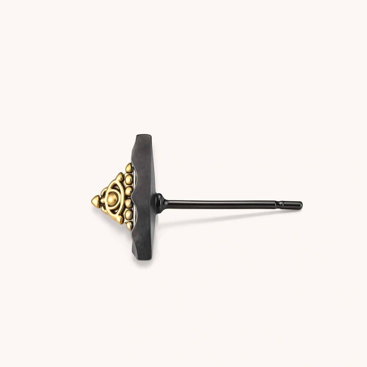 Single black triangle stud earring with a raised gold-tone center, beaded trim and eye motif on a cream background.